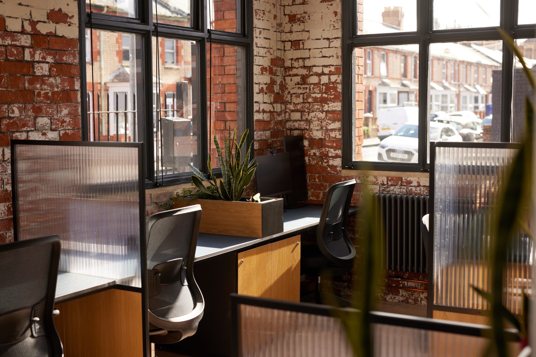 Desks in a modern office space. Reeded glass and a concrete floor.