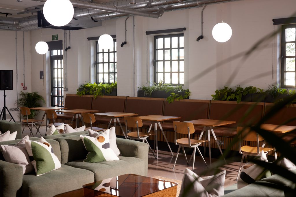 Lounge with tables, chairs and a green sofa with pillows