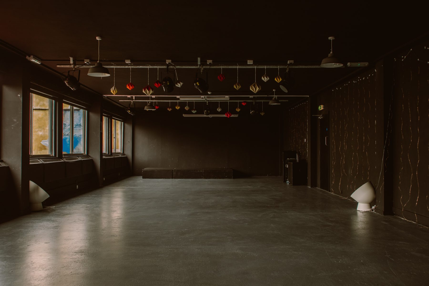 An empty event space with black floor, walls and a stage.