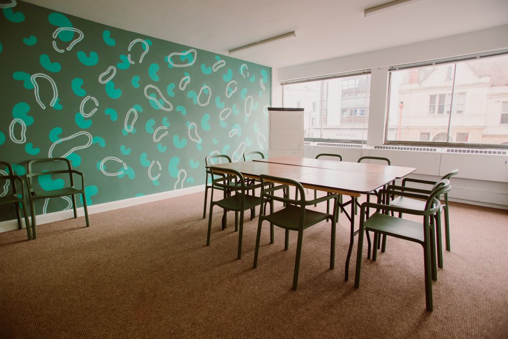 A meeting room with a green wallpaper wall, a table and chairs.
