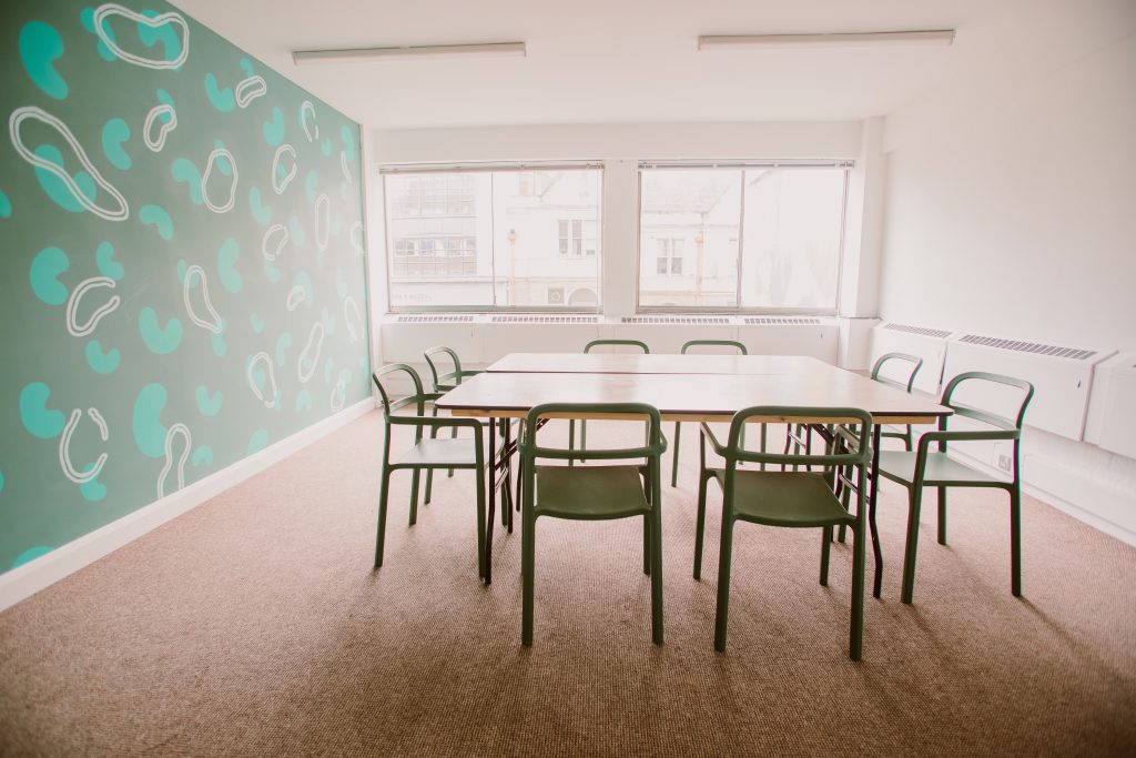 Light shining in a meeting room with green walls, table and chairs