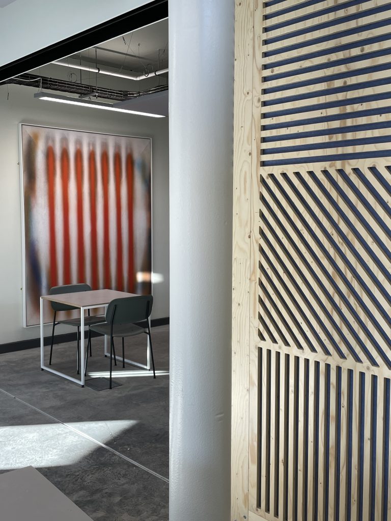 A desk with chairs in front of a piece of artwork