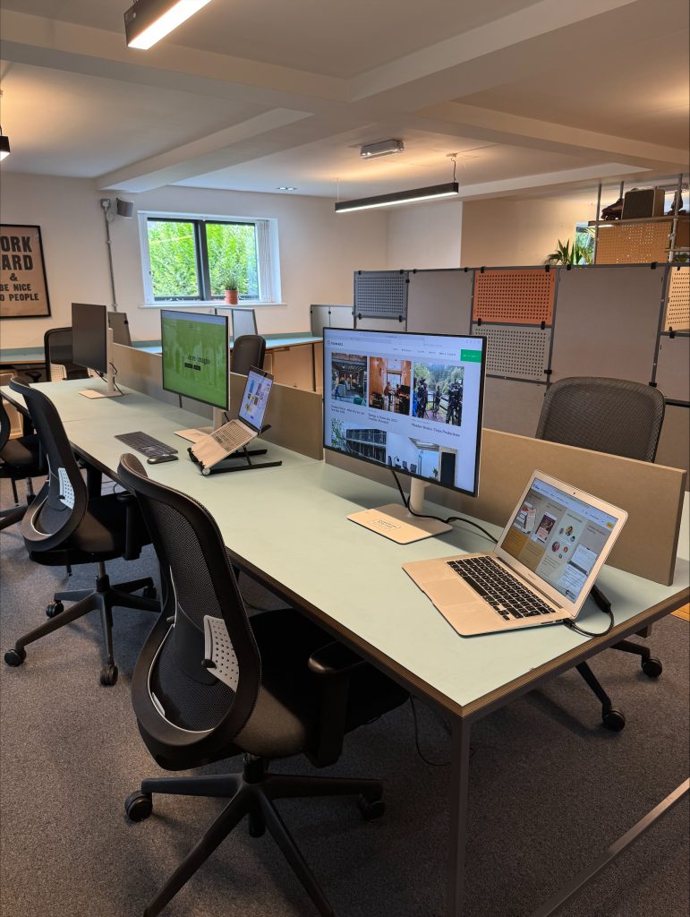 Laptops and monitors on a desk in an office space.