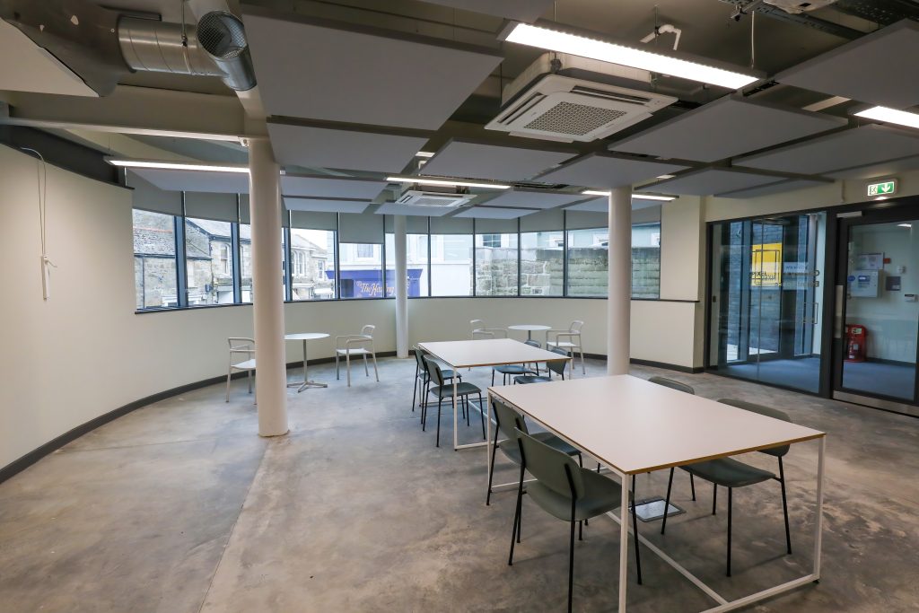 A large event space with concrete floor and tables and chairs