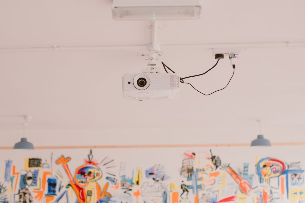 A ceiling-mounted projector in a white room