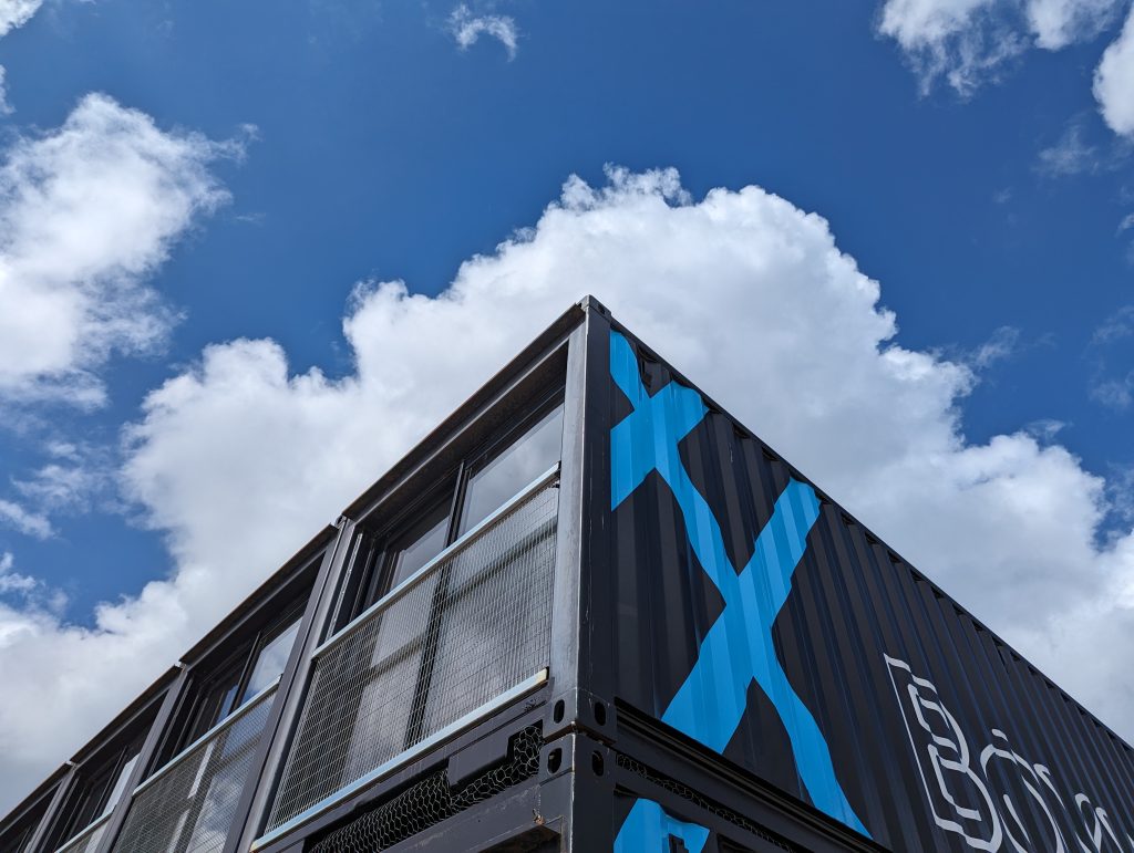 A converted shipping container with a blue sky behind it