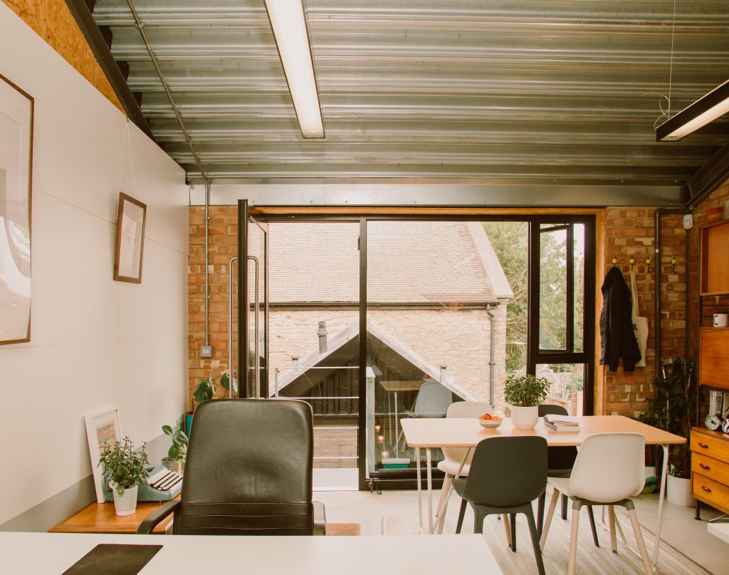 A modern office space with tables and chairs. With a large window.